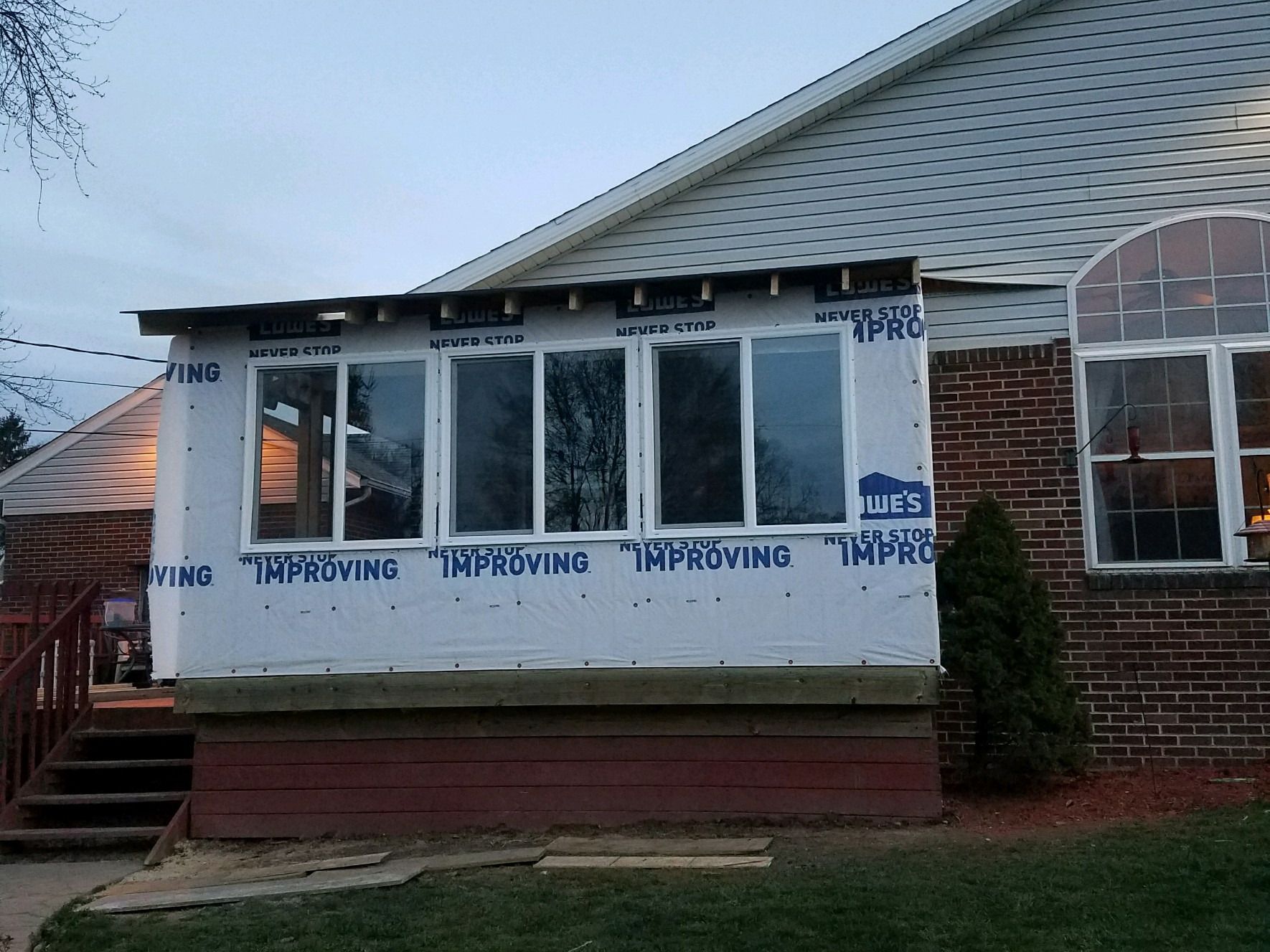 Former deck being enclosed as a sunroom, with new windows and house wrap.