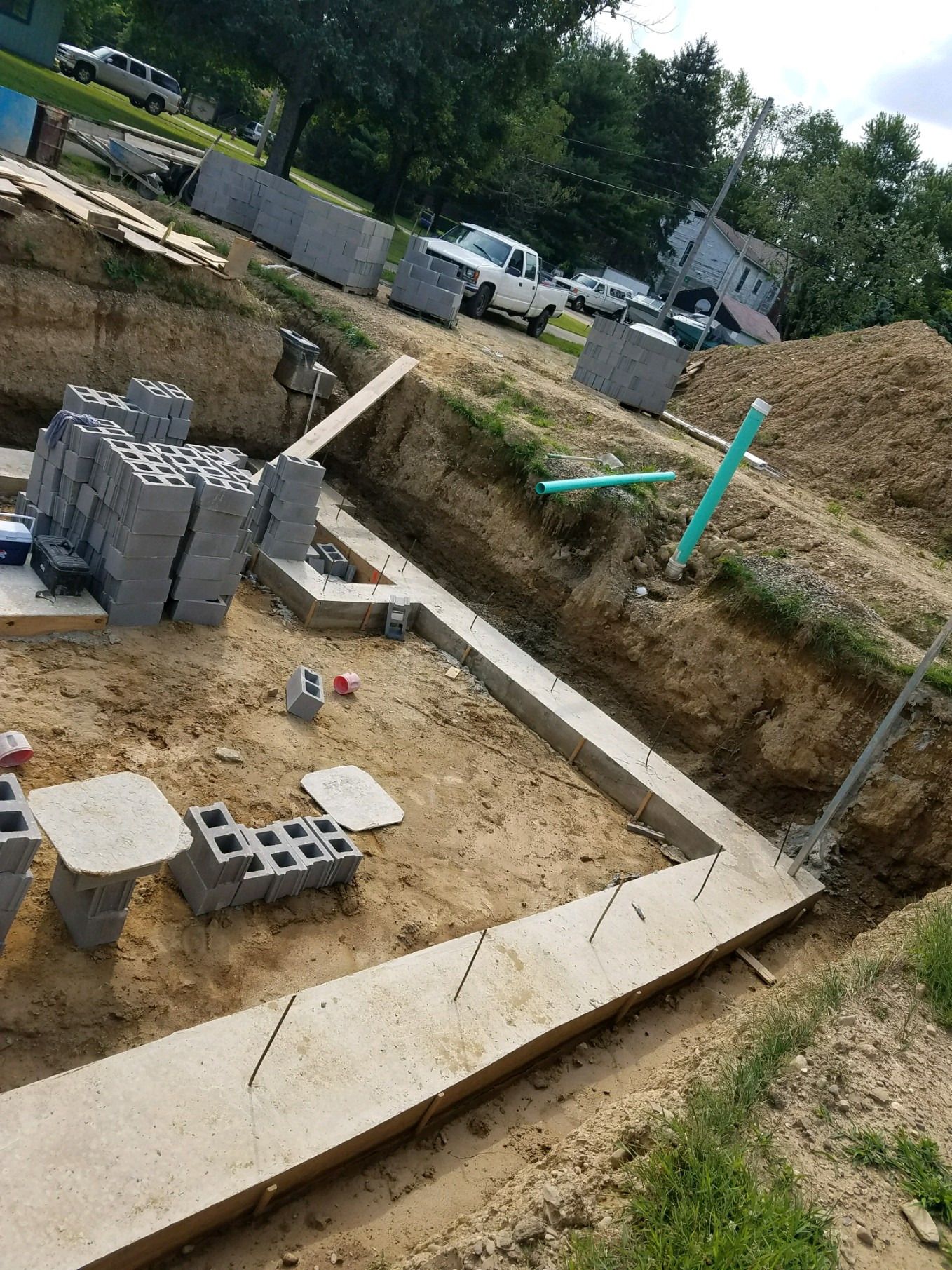Excavated site with poured footings and stacks of concrete block ready to lay.