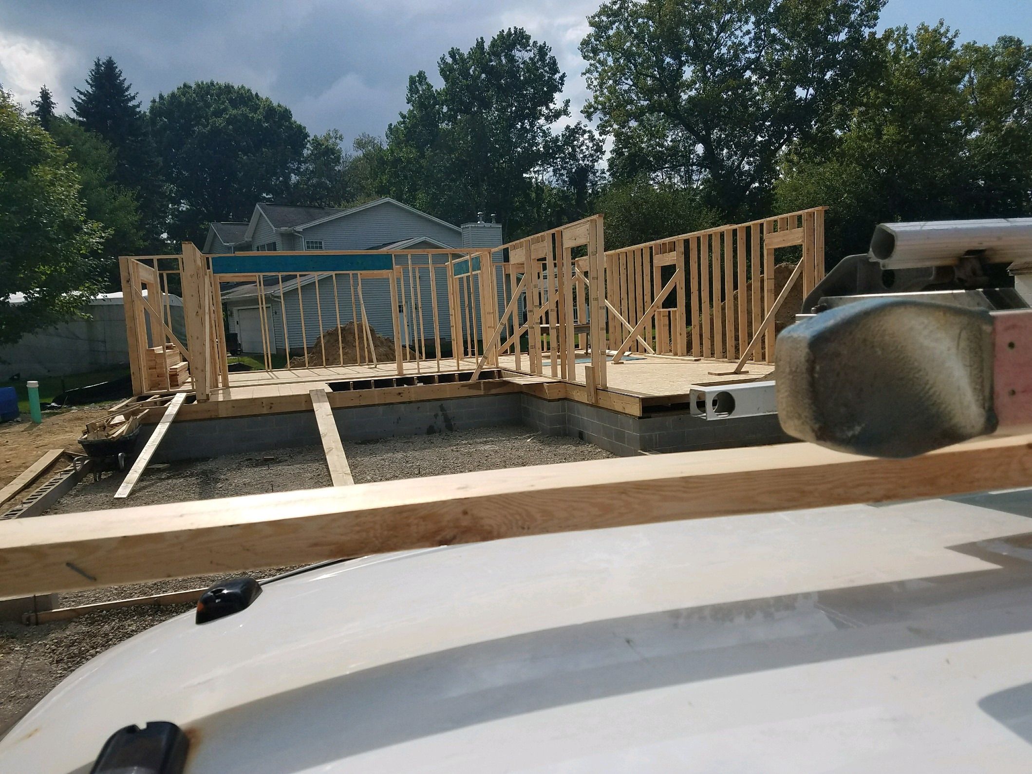 Wood-framed walls rising from the subfloor, seen over a work truck.