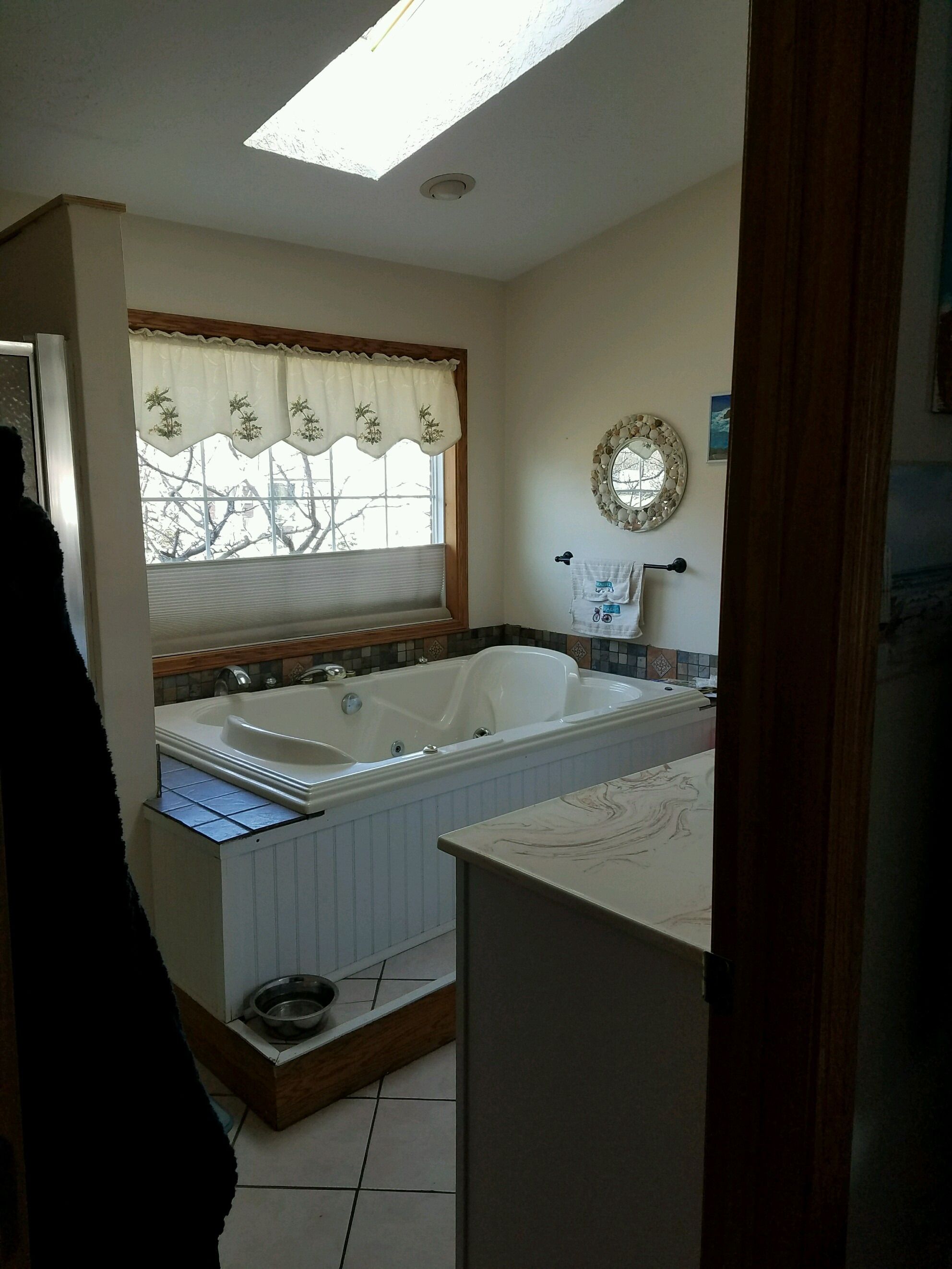 Original jetted tub under a window, with a skylight above.