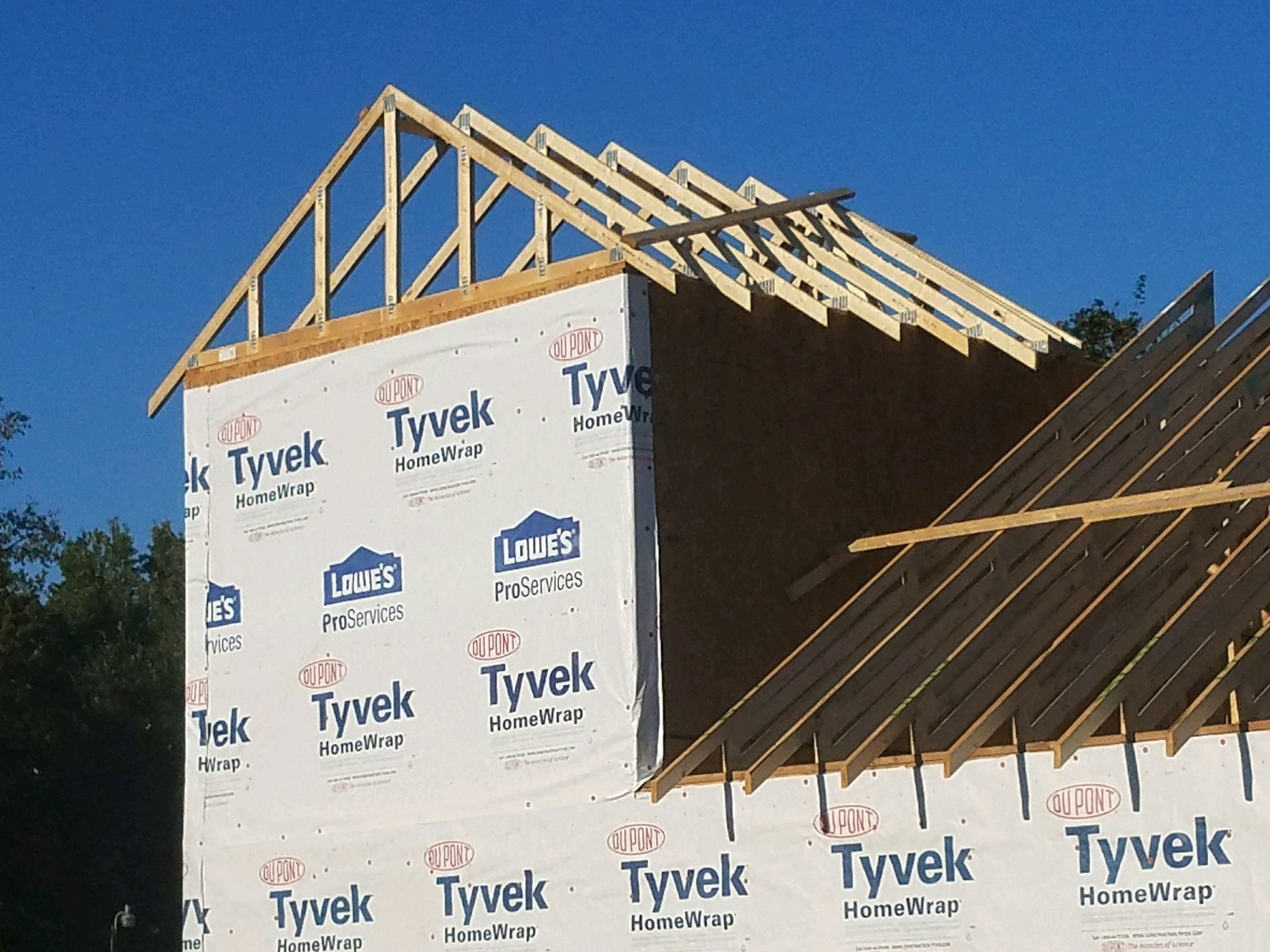 Roof trusses set on a two-story frame wrapped in house wrap.