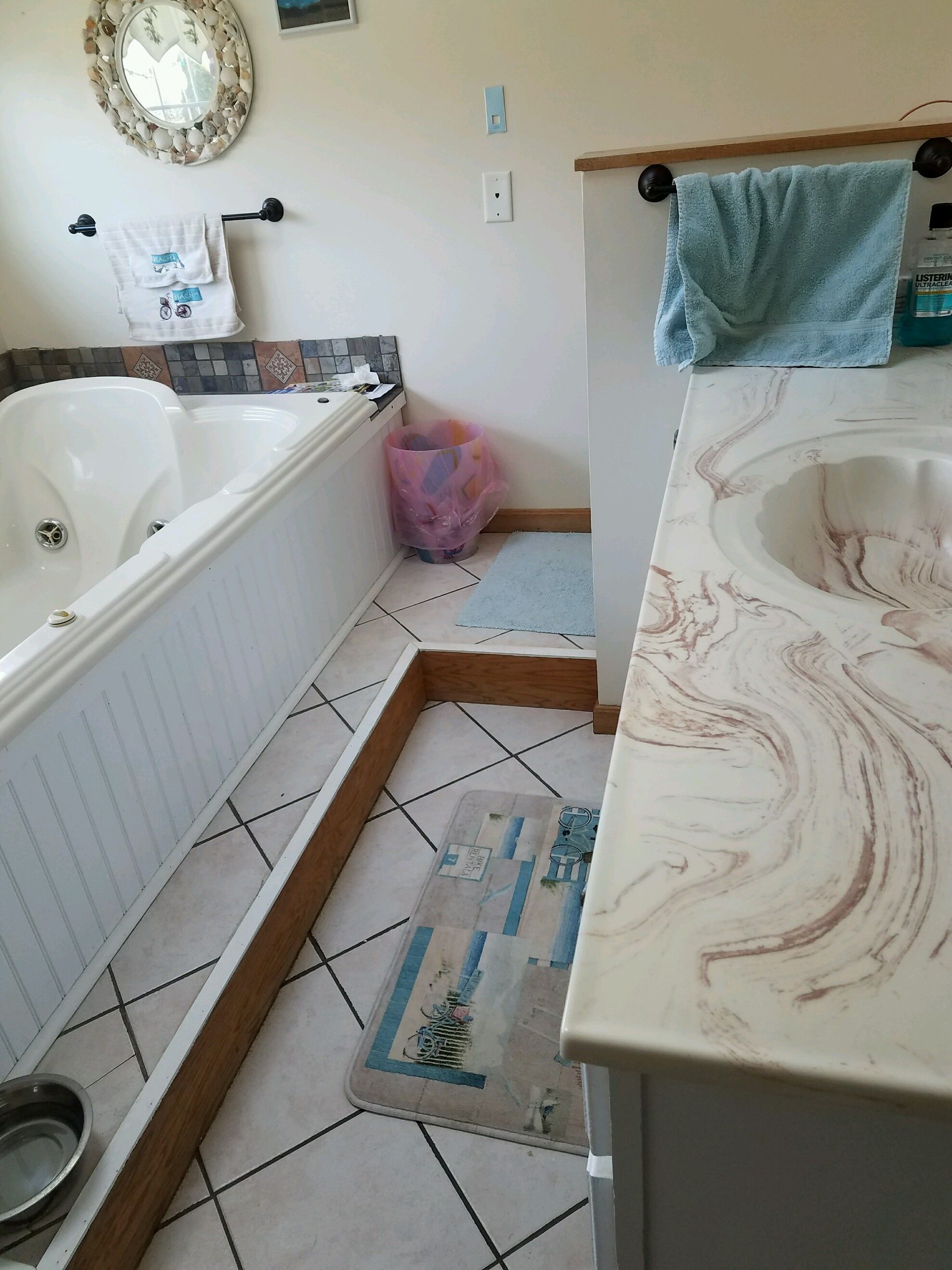 Original tub surround and tile floor next to a swirled cultured-marble vanity top.