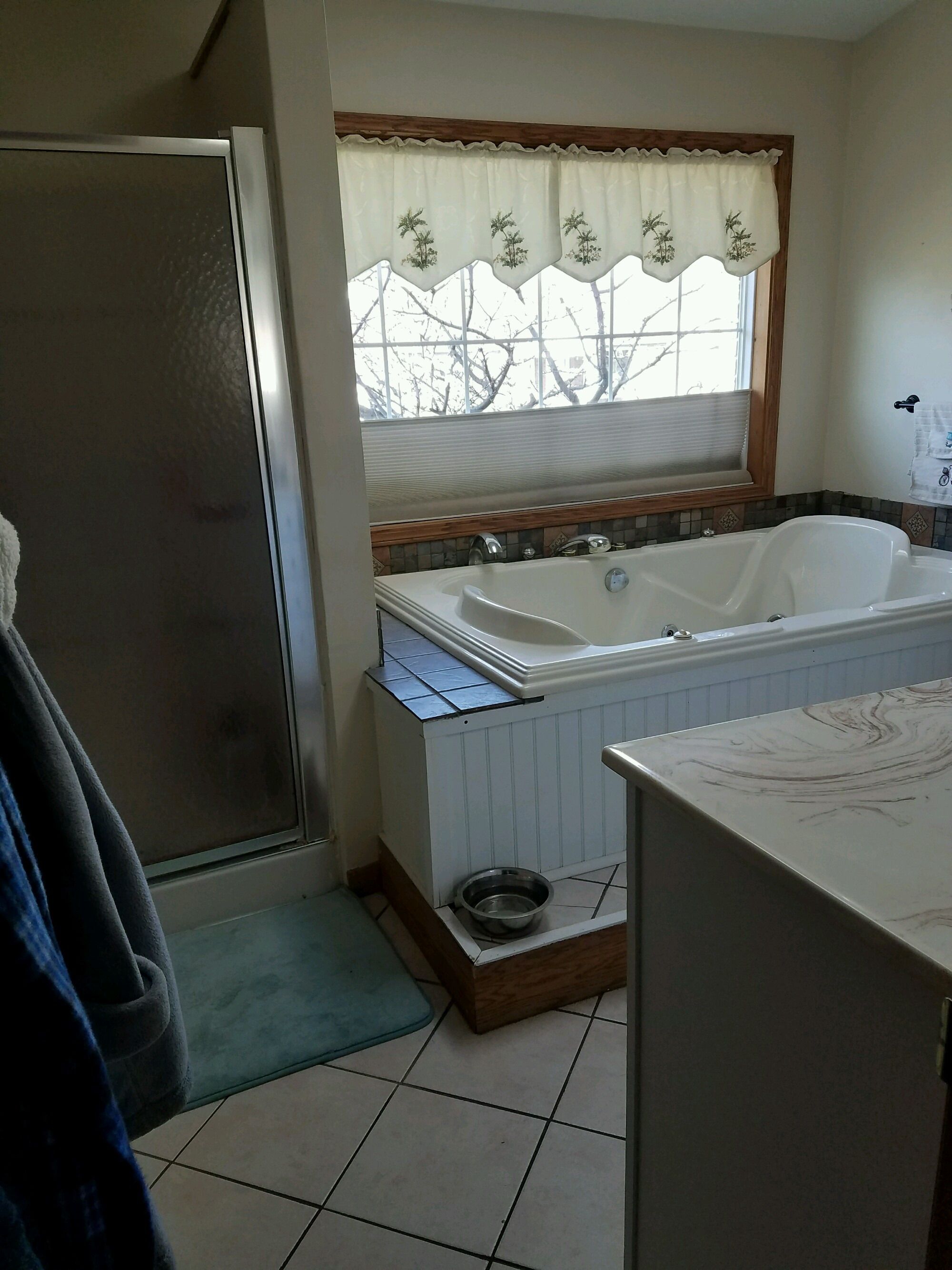 Original bathroom with a built-in jetted tub, framed shower door and tile floor.