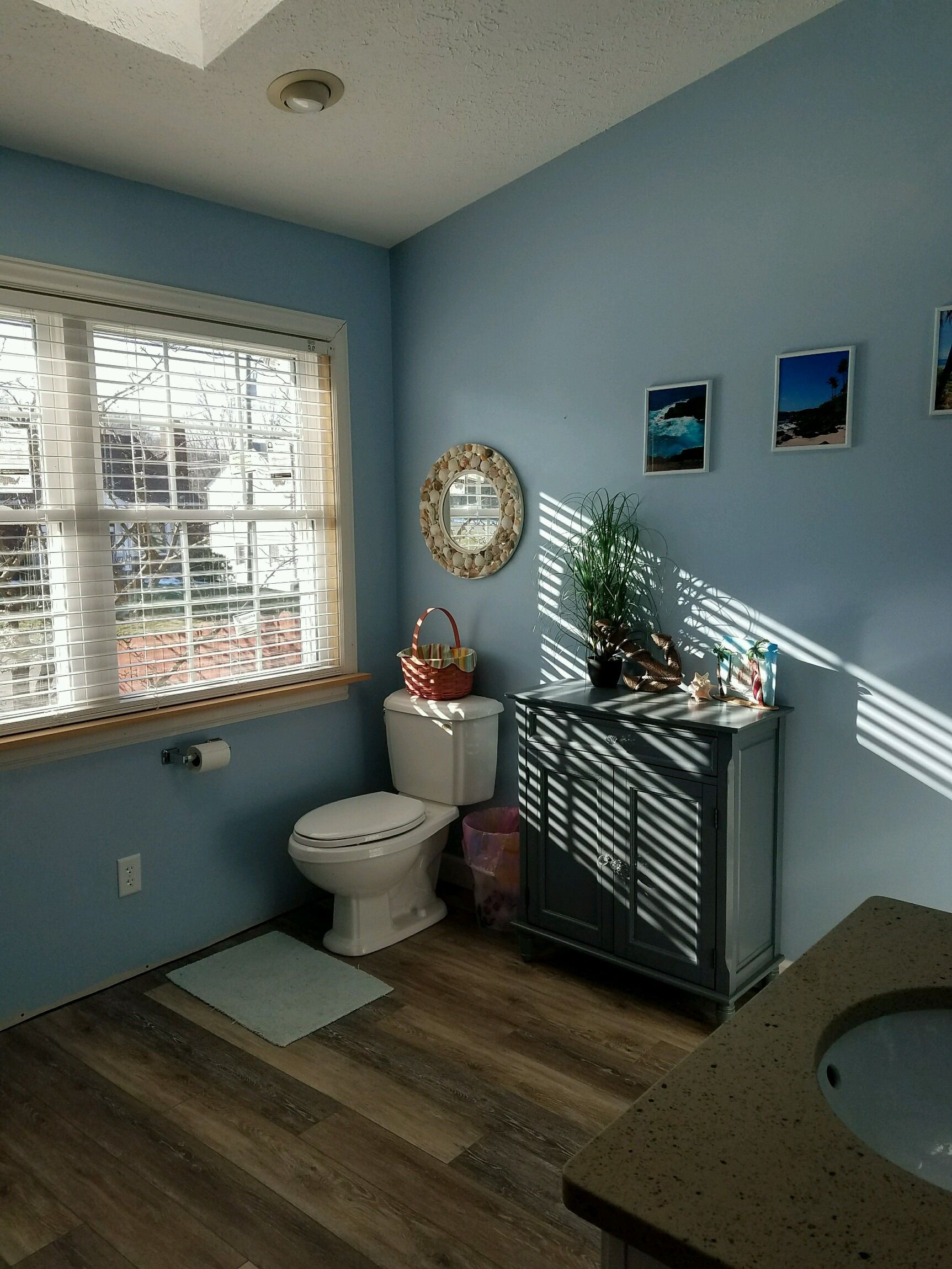 Toilet, gray storage cabinet and window in the updated bathroom.